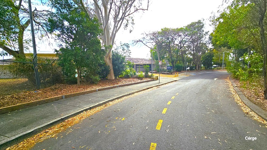 Arrival at Cleveland Aquatic Centre is through a road with continuous yellow broken lines in the middle and is surrounded by large gum trees. On the left of the road is a cemented sidewalk leading to the entrance of the centre, while on the right is a narrow, cemented curb. A chain-linked fence encloses the entire property.