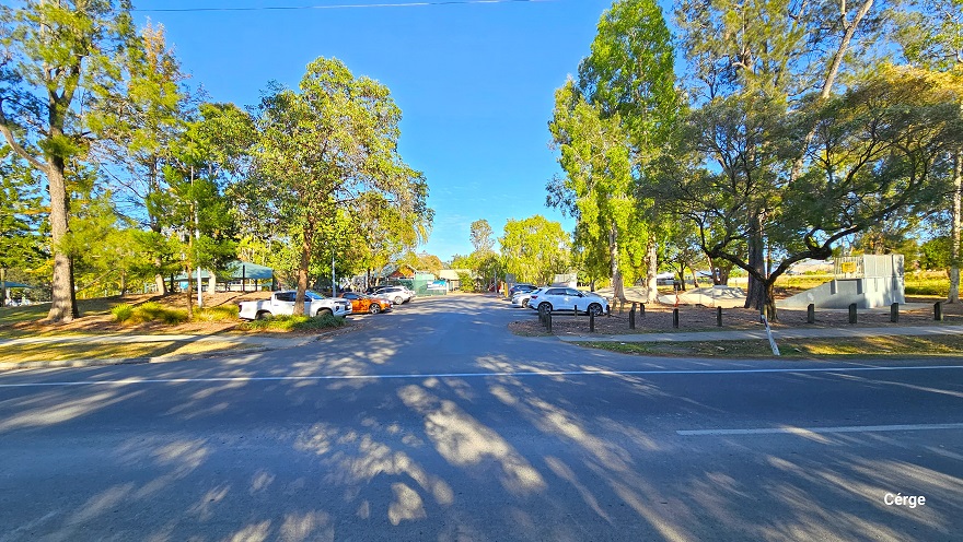 Arrival at Dayboro Pool & Gym is at a local park in Dayboro, on the corner of two main roads. The park has tall native Gum and Paperbark trees. On the sides are white diagonal road markings to regulate traffic and for emergency purposes on Mt Mee Road. This road is marked by a Mt Mee sign and a blue Showground sign with arrows pointing to the right. Following the concrete pathway to the right is the carpark.