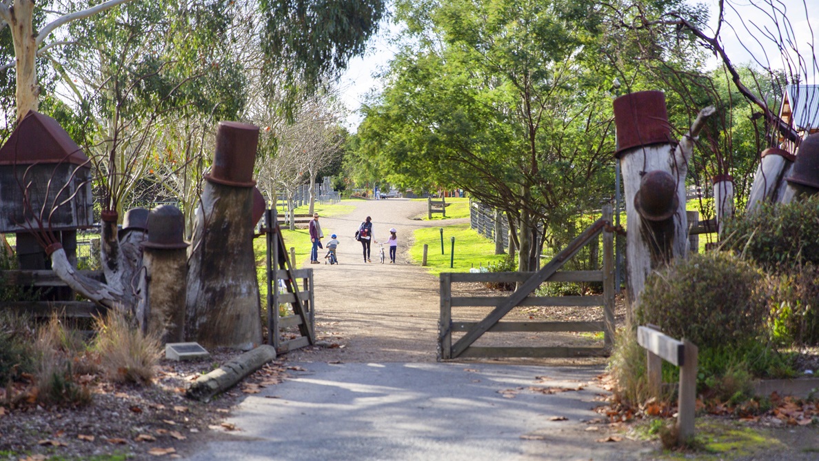 Entrance to Edendale Community Environment Farm from Southridge Carpark.  The large timber post and rail fence is topped with old rusting metal containers and various farming ornaments for an authentic effect.