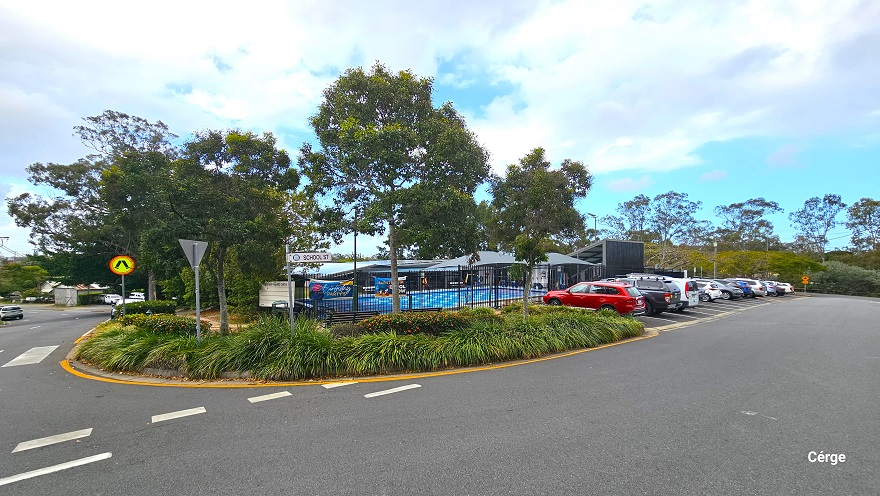 Arrival at Mudgeeraba Aquatic Centre is through the sloping road off School Street. The entire property is nestled between bushes and trees with a great leaf canopy cover. Right before the parking lot is a zebra crossing with a circular orange and yellow road sign with legs in the middle. There is a fence covering the property but is visible up the parking.