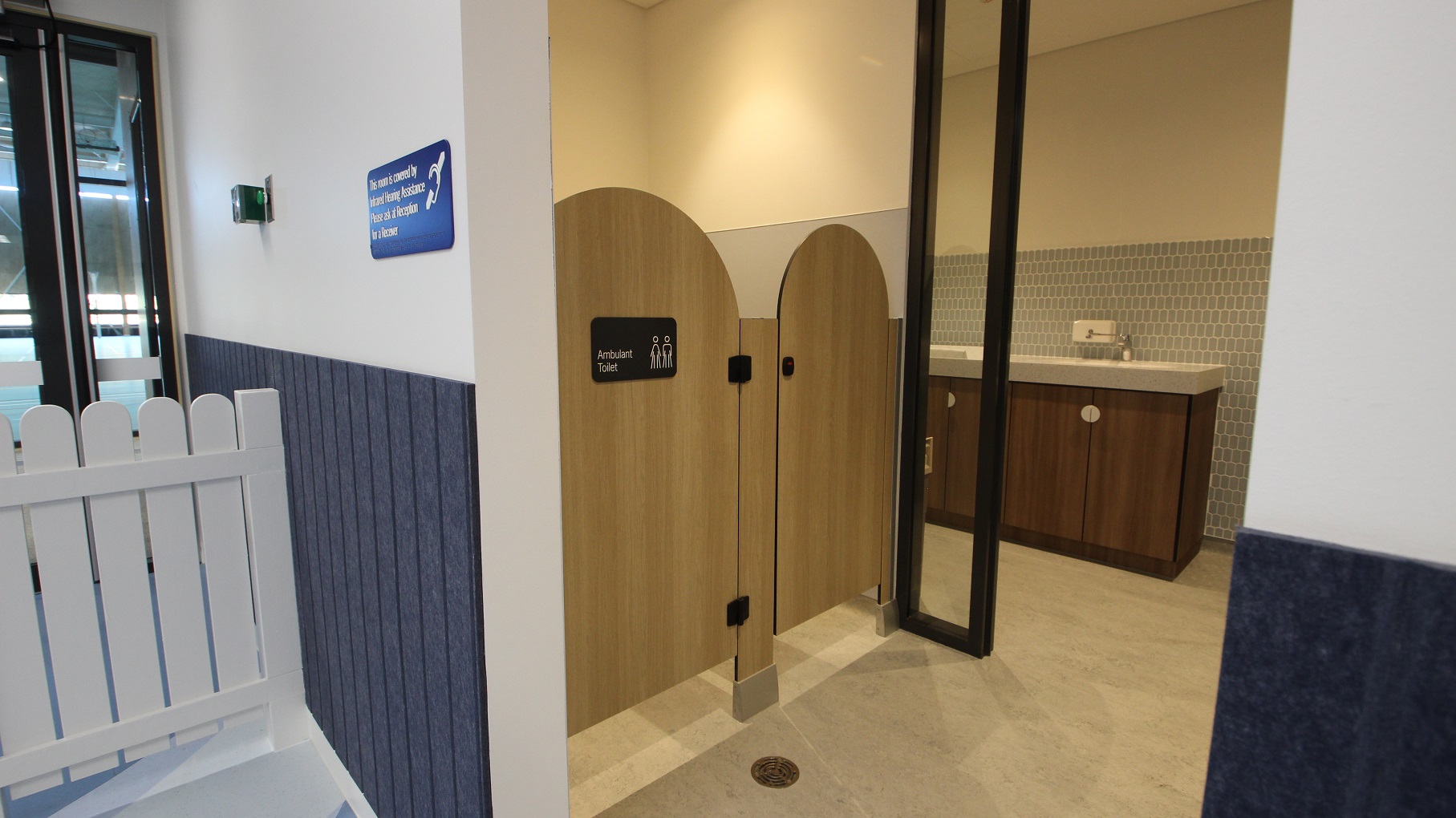 Upon entry to the Creche, you will see this section at the right side of the room. The low fence is attached to the white wall where a dark grey thick wallpaper is glued on its bottom section to provide better coverage for kids. Next to it is a wooden themed toilet that has a signage on the first cubicle door that says “Ambulant Toilet”. There’s a long black divider-like pillar that’s attached to the right wall of the toilet.