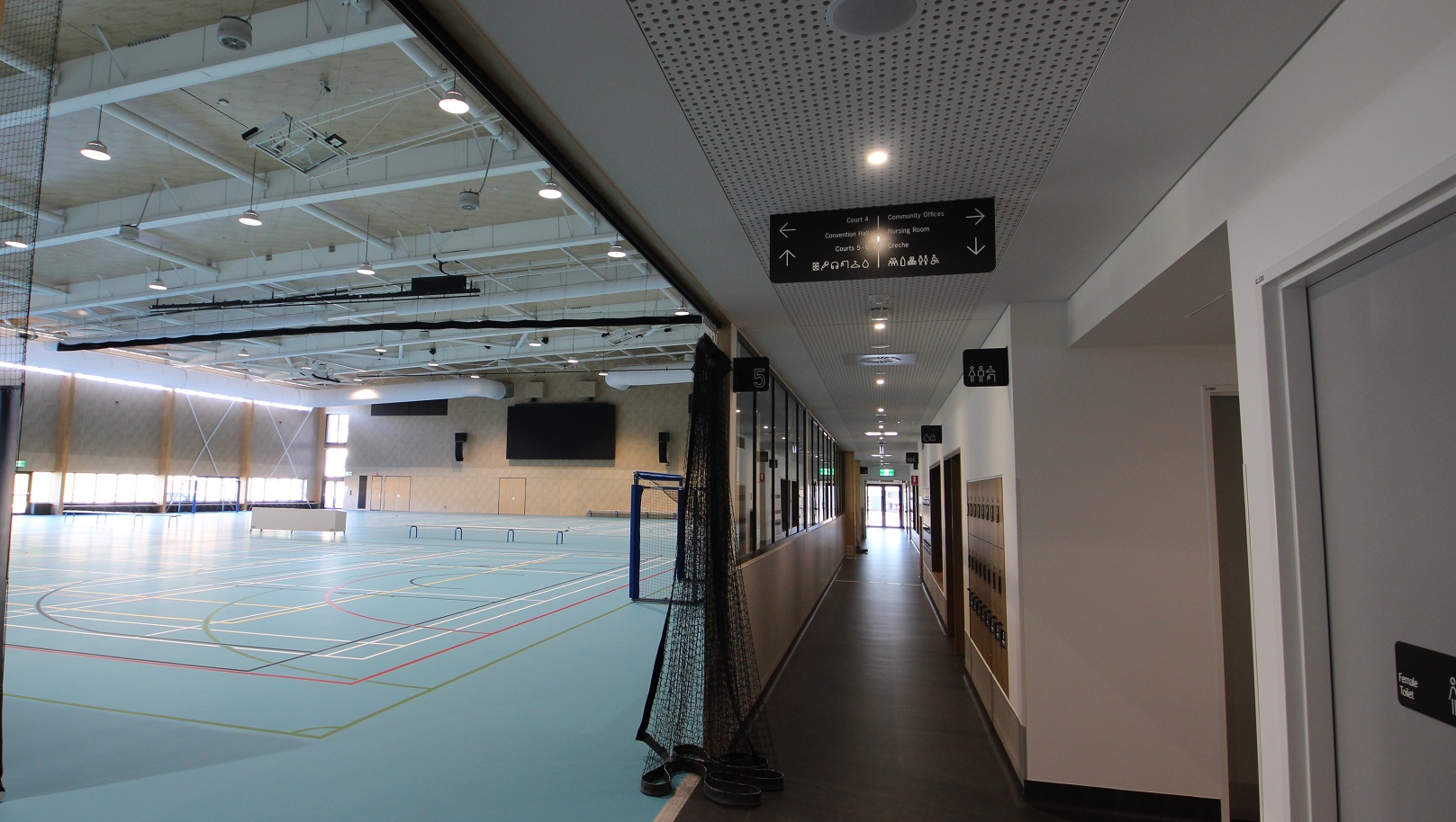 These indoor courts offer a vibrant atmosphere because of the ceiling’s white paint and good lighting. It has a pastel blue-green surface with colorful lines and curves marked on the floor. Its left side has the soccer goal and opposite to it is the glass walls with access doors in the middle. In the partition section of the two courts are available seats and tables.